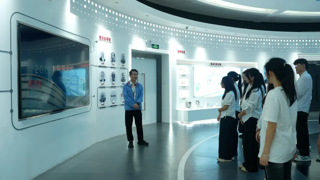 A guide presenting the company history wall in the EVE Energy exhibition hall to a visiting group