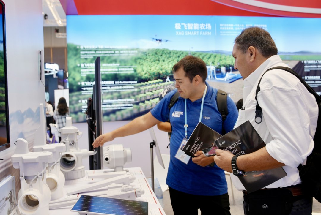 Delegates viewing XAG smart farming equipment and field IoT devices at an agricultural technology exhibition.